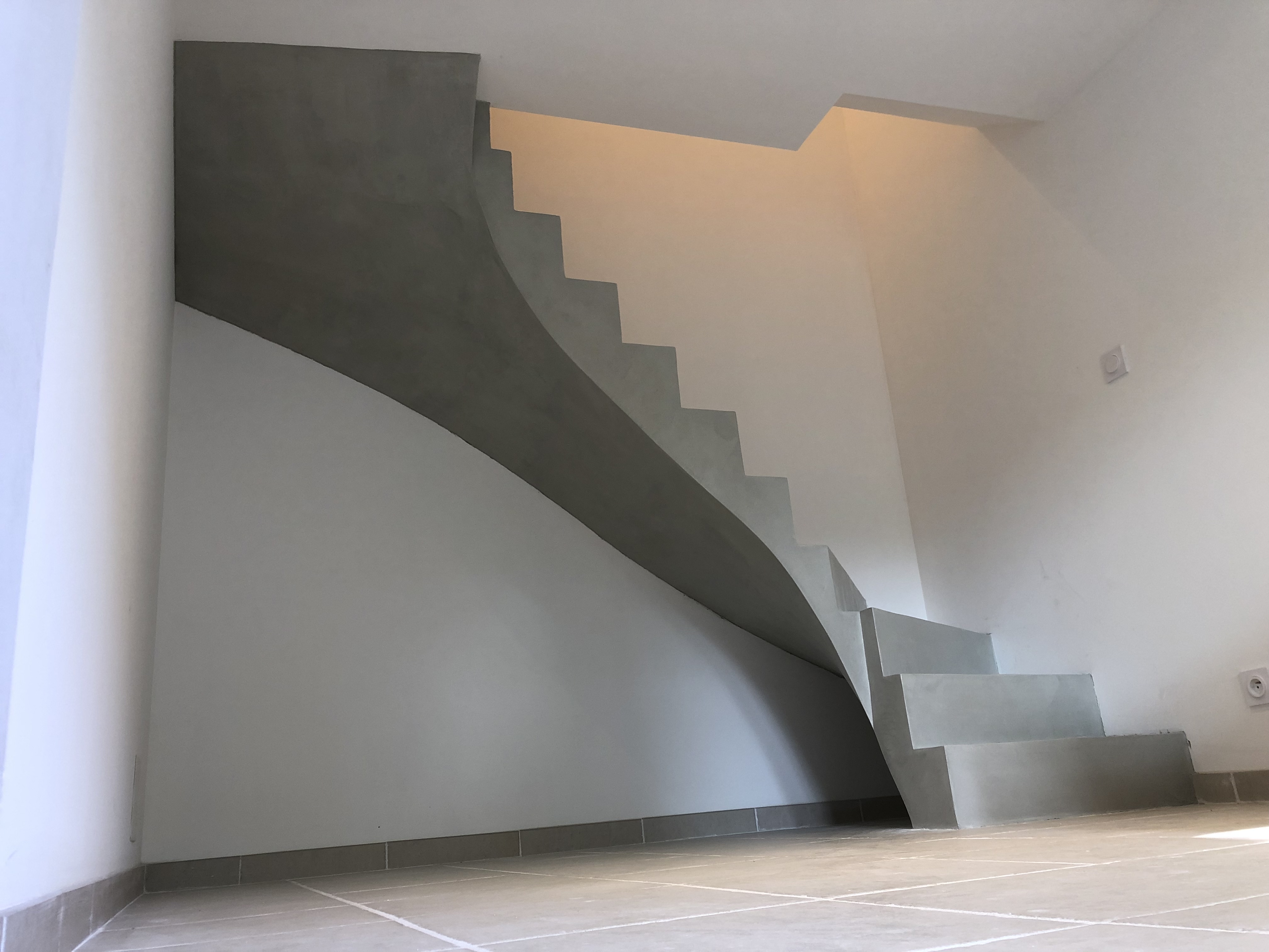 audacieux escalier à paillasse deux quart tournant en béton ciré vernis soyeux couleur gris perle à Royan en Charente maritime dans la région nouvelle aquitaine pour un particulier