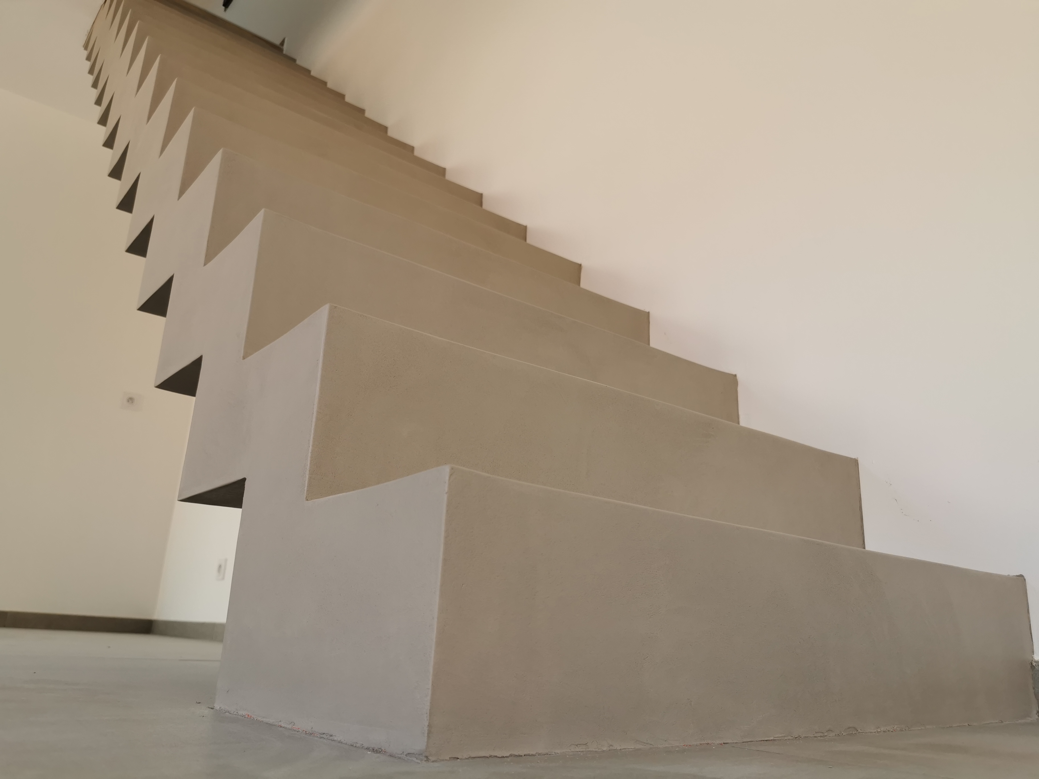 sublime escalier crémaillère dans une pièce à vivre en béton ciré vernis mat couleur galet original À arcachon proche Bordeaux pour un architecte