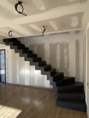 Escalier à crémaillère en béton lissé, finition en vernis mat velouté et teinte anthracite, dans une maison à Cambernard à côté de Toulouse. Finitions et couleurs multiples avec le béton ciré.