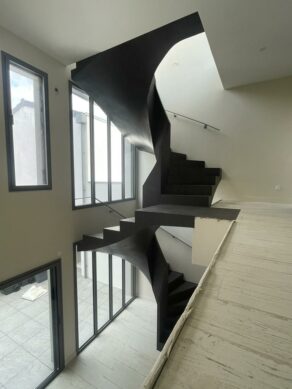 Construction d'un escalier tournant teinté en gris anthracite, dans une maison moderne, en région Nouvelle-Aquitaine.